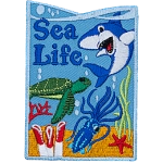 A shark, turtle, and squid swim over coral and seaweed on this vertical Sea Life patch.