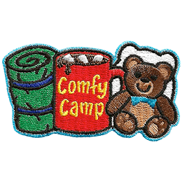 From left to right is a sleeping bag, a mug of coco with the words 'Comfy Camping' on the side, and a teddy bear with a pillow behind it.