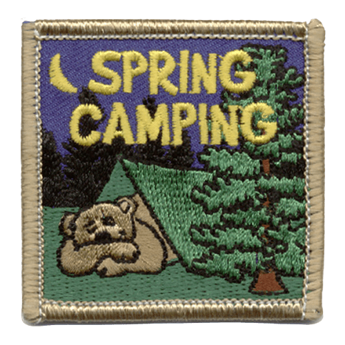 A brown bear sleeps in a tent in the middle of the forest. Spring Camping is stitched above the tent.