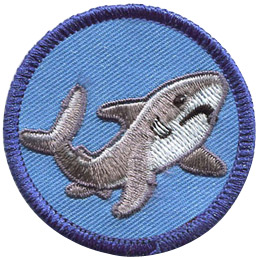 This round badge displays a grey shark in a curved 'U' position with it's tail on the left and head on the right.