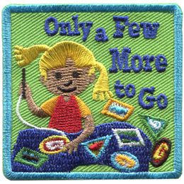 A young girl sews patches and crests onto a navy blue blanket. There are three patches sitting off to the side that haven't been sewed onto the blanket yet. Text on the crest reads, 'Only a Few More to Go.'