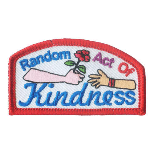 A hand is passing a poppy to another hand with the words random act of kindness printed above and below.