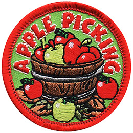 A wooden bucket is overflowing with apples, with three resting on the leaves just outside of the bucket. The text \'Apple Picking\' arches above the bucket near the top of this round crest.