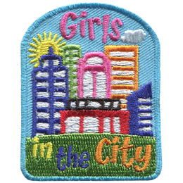 A sunny cityscape sits on top of a green hill. The words Girls In The City are embroidered at the top and bottom.