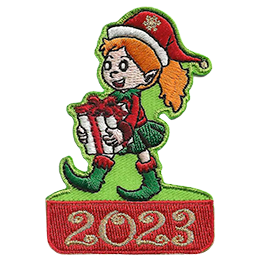 A happy elf with a wide smile and a ponytail of red hair carries a white present with a red ribbon. The date 2023 is below them.
