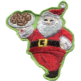 Santa Clause proudly holds up a tray of cookies and gives a big jolly smile.