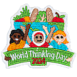 Three girls hold up a world thinking day banner with a bowl of food behind them.
