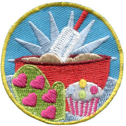 A bowl of batter, an oven mit and a cupcake are in the center of this circular patch.