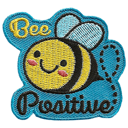 A cute bee has dots for eyes and a big U-shaped smile. The words Bee Positive are stitched above and below the bee. 