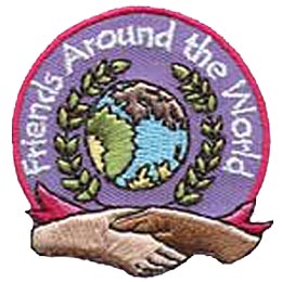 A globe is surrounded by a wreath of leaves which in turn is surrounded by the words ''Friends Around The World.'' Two hands shake at the bottom of the patch.