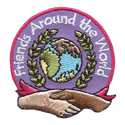 A globe is surrounded by a wreath of leaves which in turn is surrounded by the words ''Friends Around The World.'' Two hands shake at the bottom of the patch.