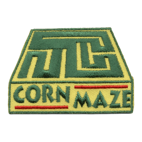 This square patch depicts a green hedge corn maze winding through a yellow box. The words ''Corn Maze'' are embroidered at the bottom of the patch.