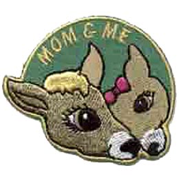 A doe and a fawn are resting their heads against each other. Mom & Me is stitched in an arc above them.