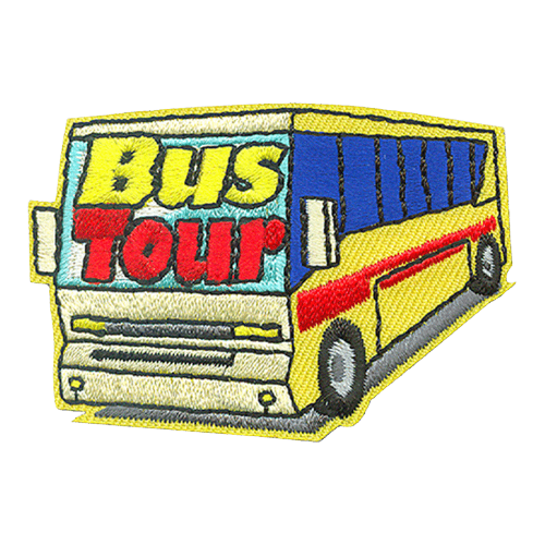 A yellow tour bus with blue tinted windows drives towards you. The words ''Bus Tour'' are embroidered on the front windshield.