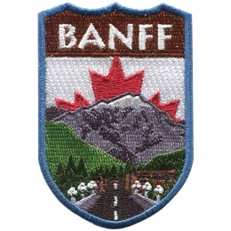 This emblem has the name 'Banff' at the top on a brown background. Just below it, front and center, is a paved road lined with lights leading to Banff itself. A green forest, complete with a waterfall and a towering snow-capped mountain, rests behind Banff. The center portion of Canada's red and white flag peaks out from behind the mountain.