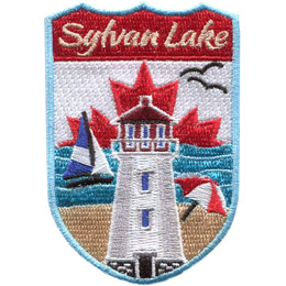 This crest displays a lighthouse front and center. Behind the lighthouse (bottom of the patch up) is a sandy beach, the waves of a lake, a maple leaf on a white background, and the words 'Sylvan Lake'. An umbrella is open on the beach, a sail boat rides the waves, and two birds fly in the white background.