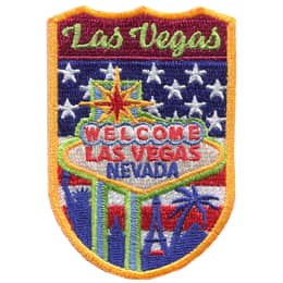 This shield shaped crest showcases Las Vegas. The name is at the top, underneath that is the welcome sign of Las Vegas Nevada followed by iconic landmarks. The background is the USA\'s flag.