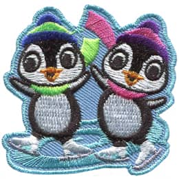 Two adorable penguins skate on a swirl of ice. Both penguins wear winter hats and scarves.