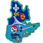 This patch is in the shape of the Canadian province of Quebec. From top to bottom, the Flue-de-lis, a jug of maple syrup, hockey stick and puck, Bonhomme, and Quebec City.