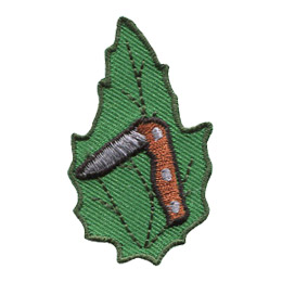A folding knife is partially open on a green leaf.